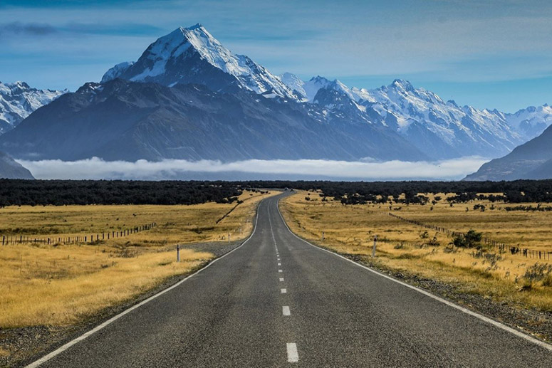 Road leading to a high snow-capped mountain at Mount Cook National Park, New Zealand