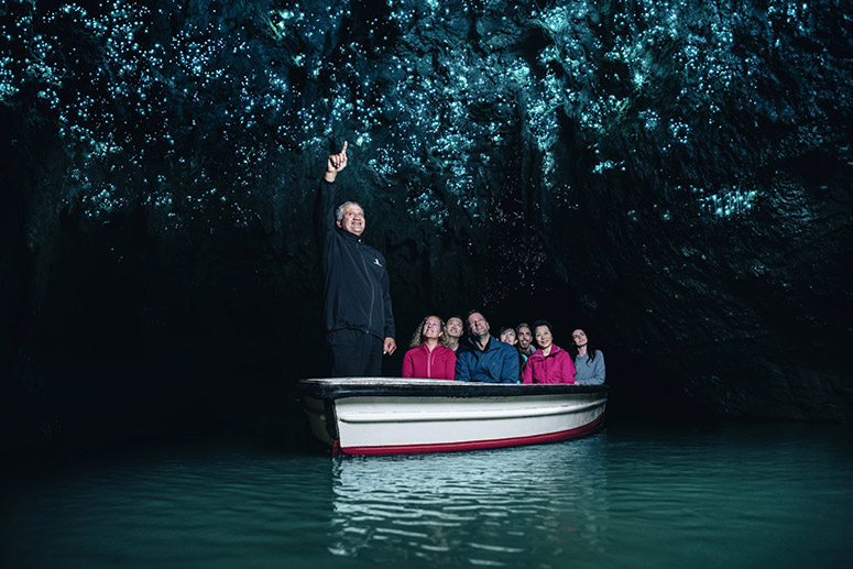 Waitomo Caves boat tour guide pointing out glowworms to visitors