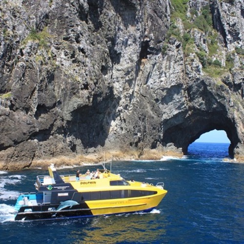 Jet boat on water passing a large rock island