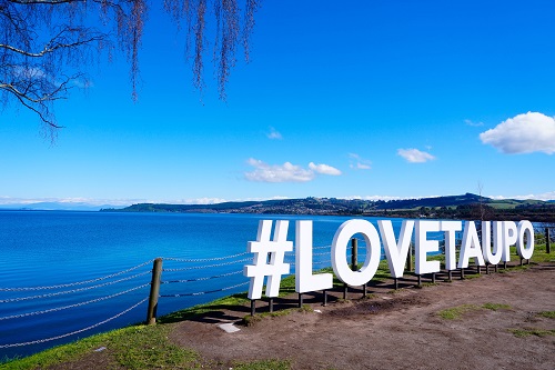 Sign saying Love Taupo in front of a blue lake at Lake Taupo, New Zealand