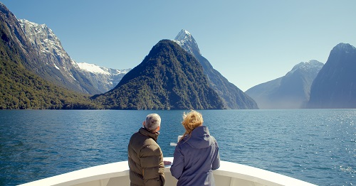Discovering Milford Sound on a boat tour at Fiordland National Park, New Zealand A man and woman looking out over a lake with mountains in the background at Milford Sound