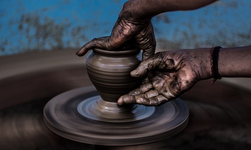 The hand of a potter forming a vase on a pottery wheel