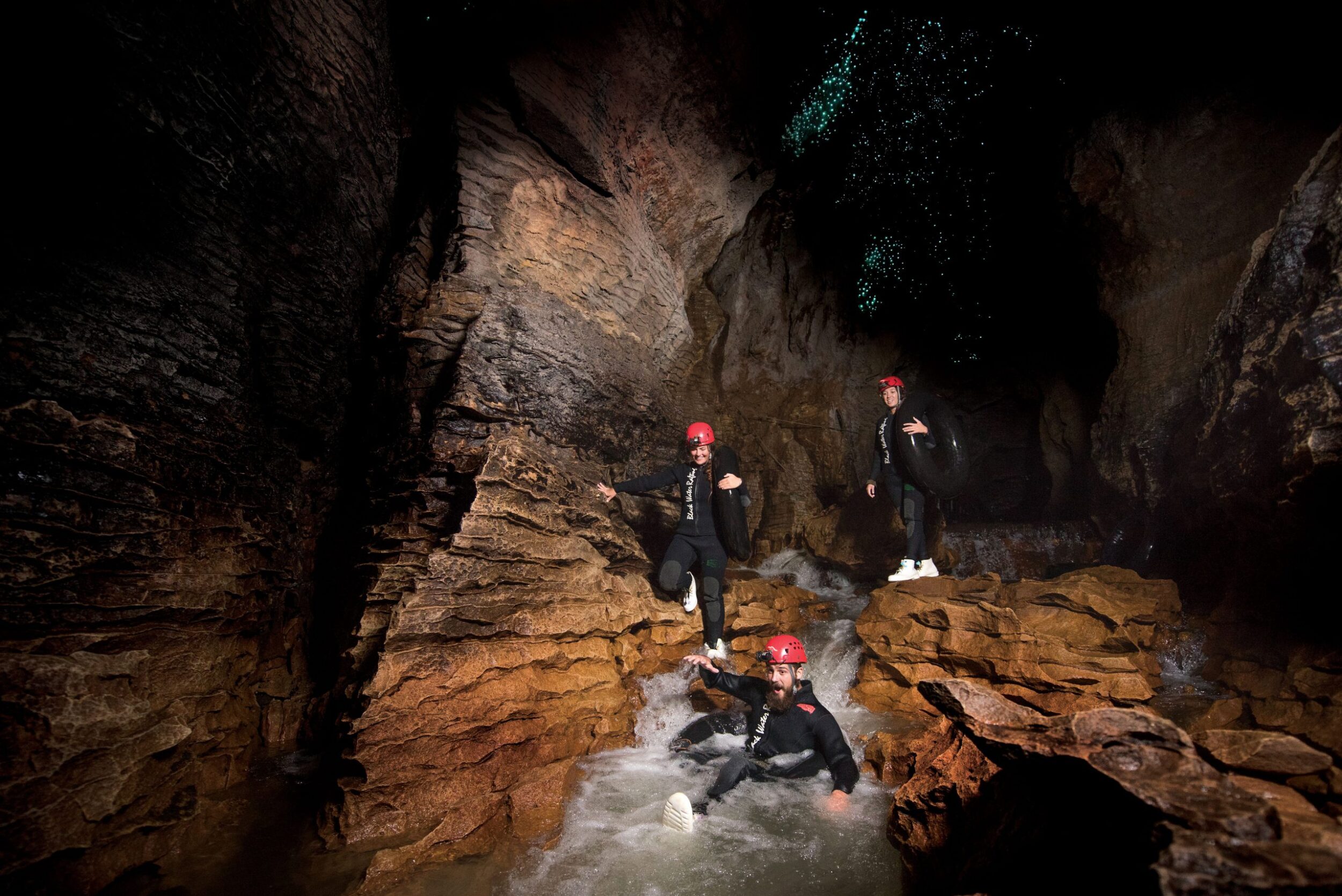 Black Water Rafters sliding down underground waterfalls at Waitomo Caves